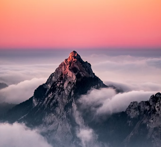 Mountain peak above clouds at sunset